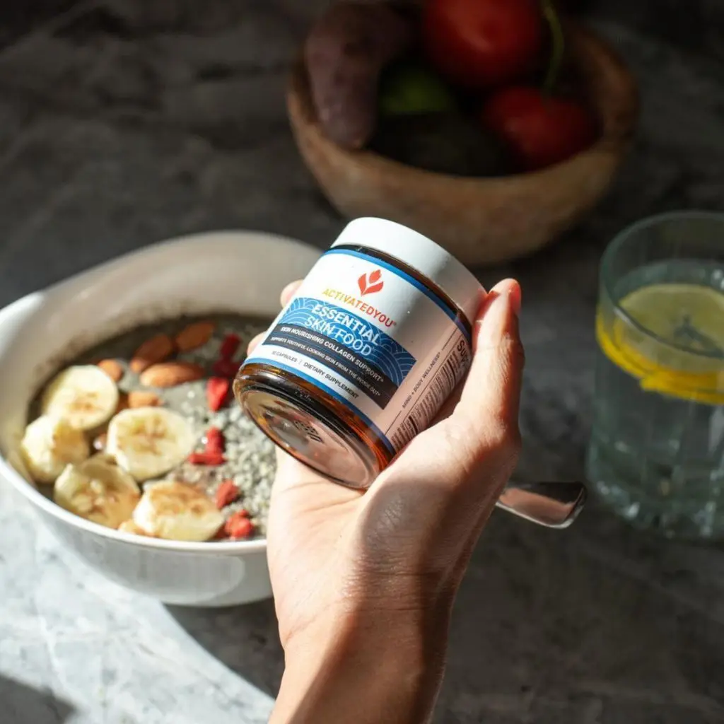A hand holding a jar of Essential Skin Food with a bowl of chia pudding in the background