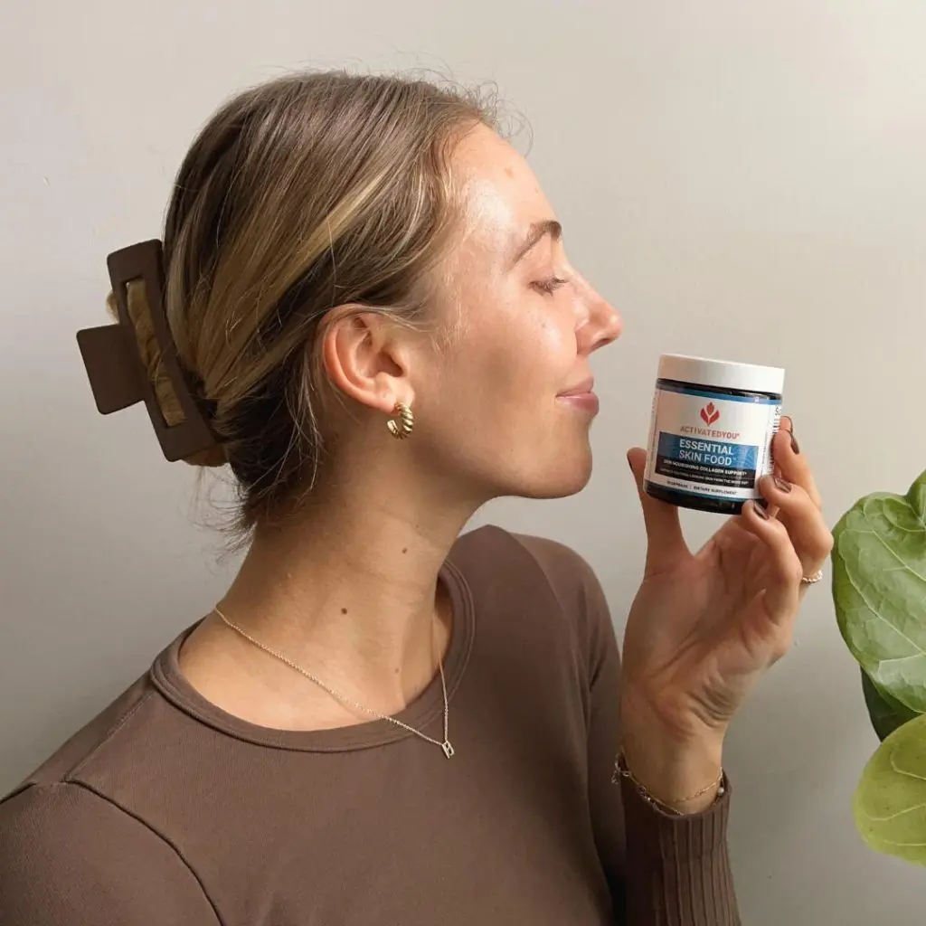 A woman holding a jar of Essential Skin Food up to her face