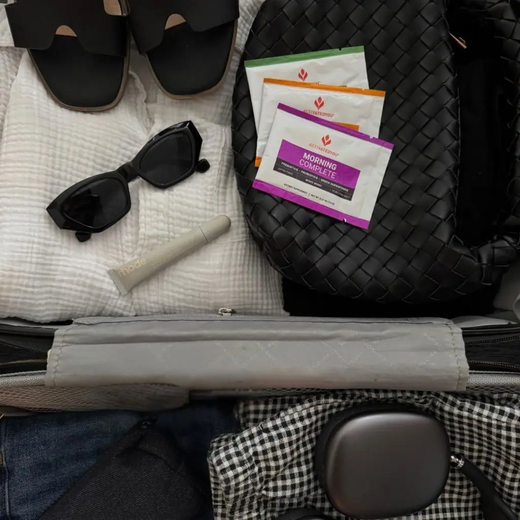 A top-down view of packed luggage with a set of Morning Complete Variety Packs on top